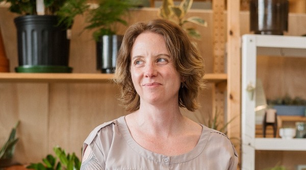 Smiling woman stands in plant shop.