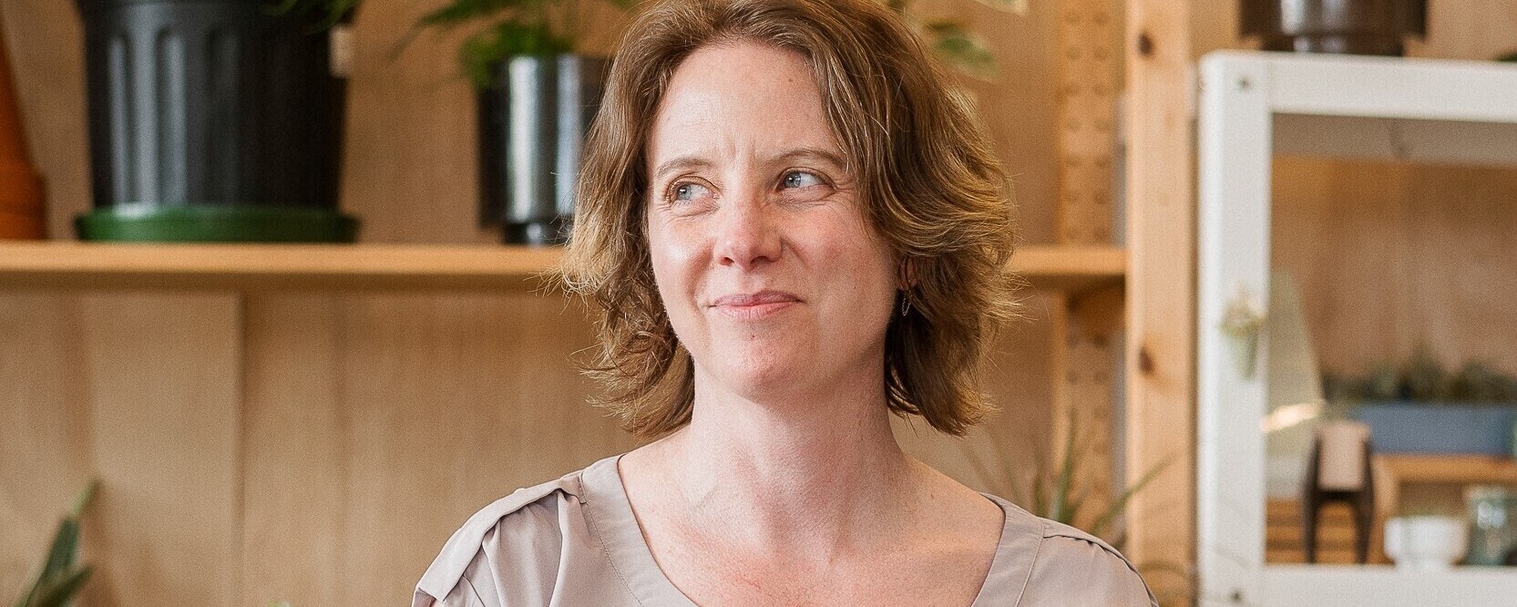 Smiling woman stands in plant shop.