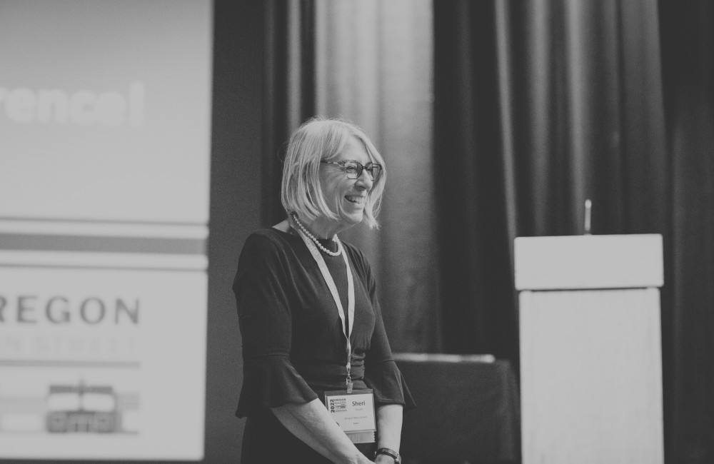 Black and white photo of a woman laughing in front of a podium.