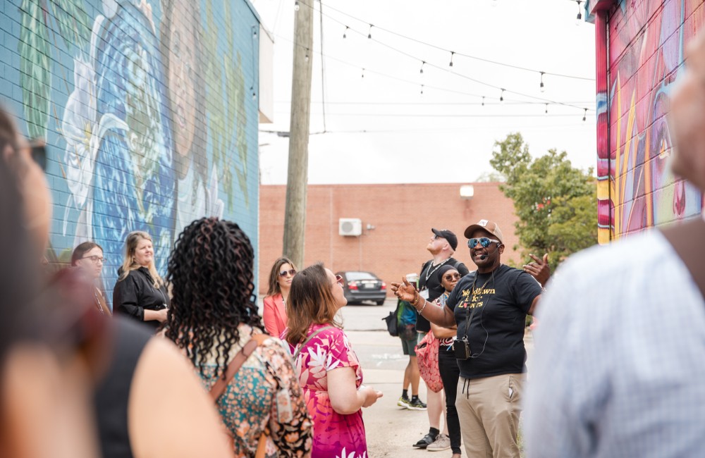 A speaker addresses a crowd of people on a walking tour.