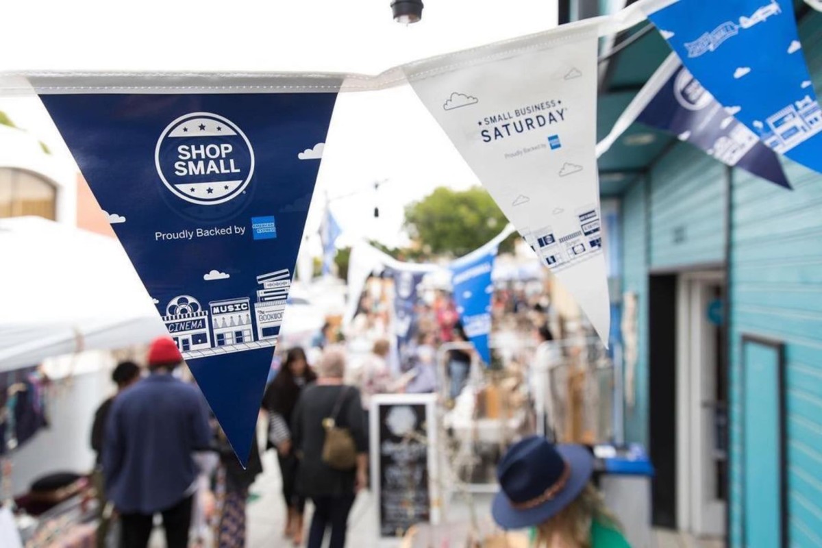 American Express Shop Small Small Business Saturday flags hang over a busy downtown.