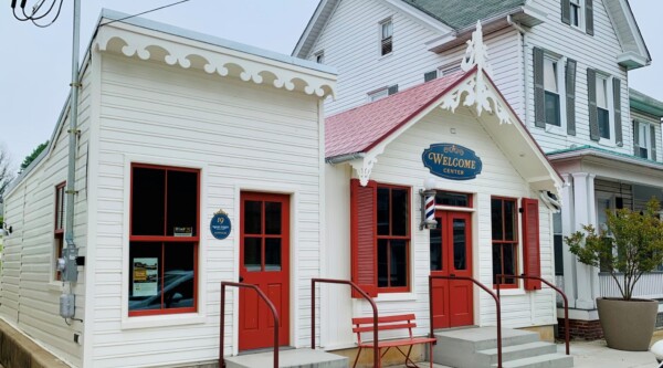 Completed rehabilitation of the historic structures with white paint, decorative woodwork, red shutters and doors, and the Main Street sign