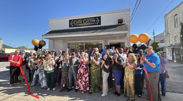 A group of people poses after a ribbon cutting outside a small business
