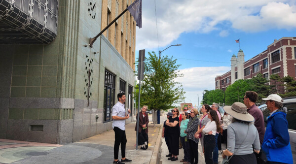 Tour group visiting an Art Deco building while listening to a speaker.