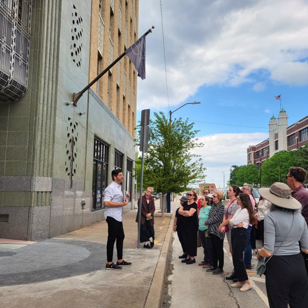 Tour group visiting an Art Deco building while listening to a speaker.