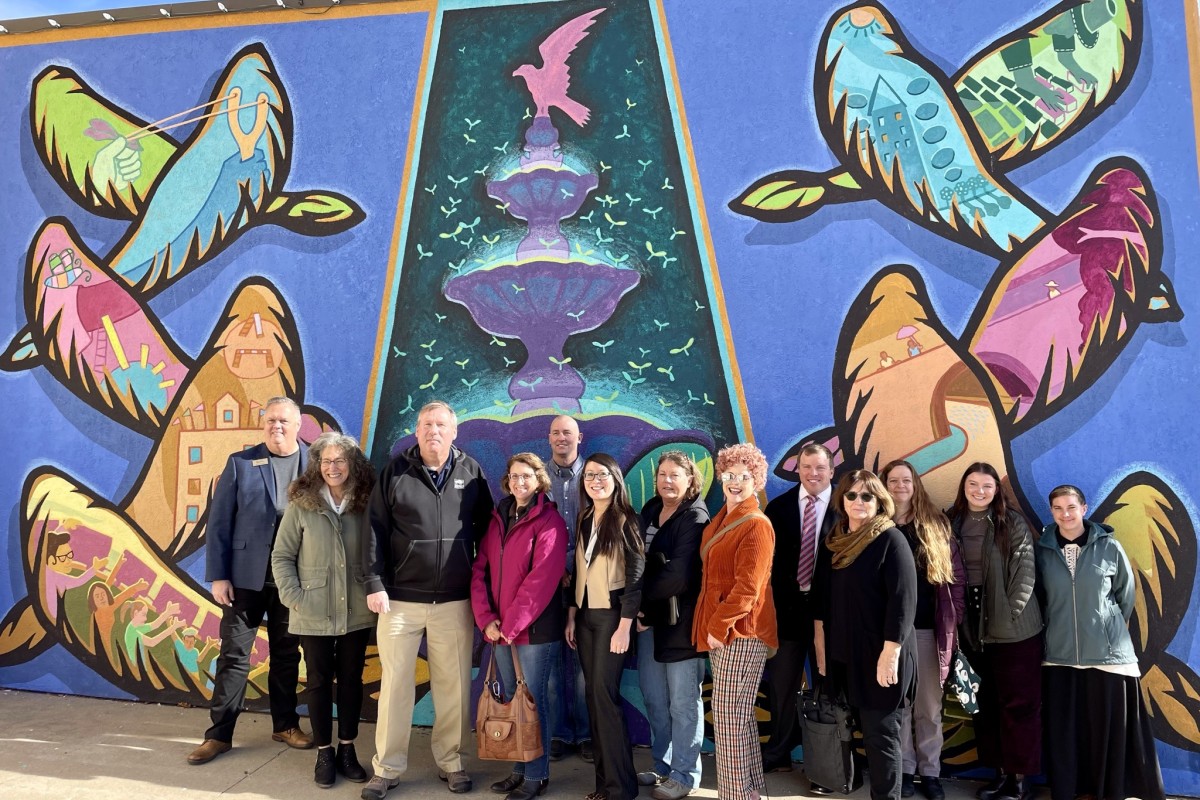 Main Street America staff and local program staff stand in front of a mural in Baldwin City, Kansas.