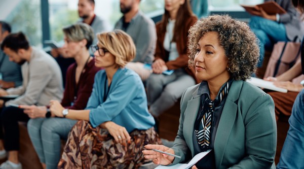 Adult professionals taking notes while participating in an education event.