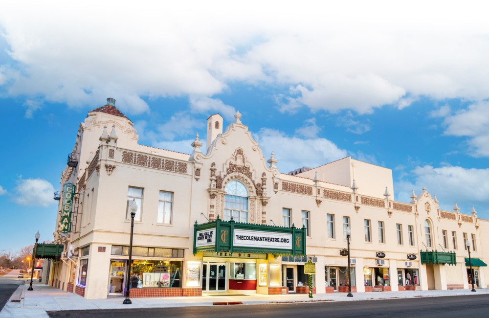 Street view of a beautifully preserved historic theater with a white facade and green marquee.