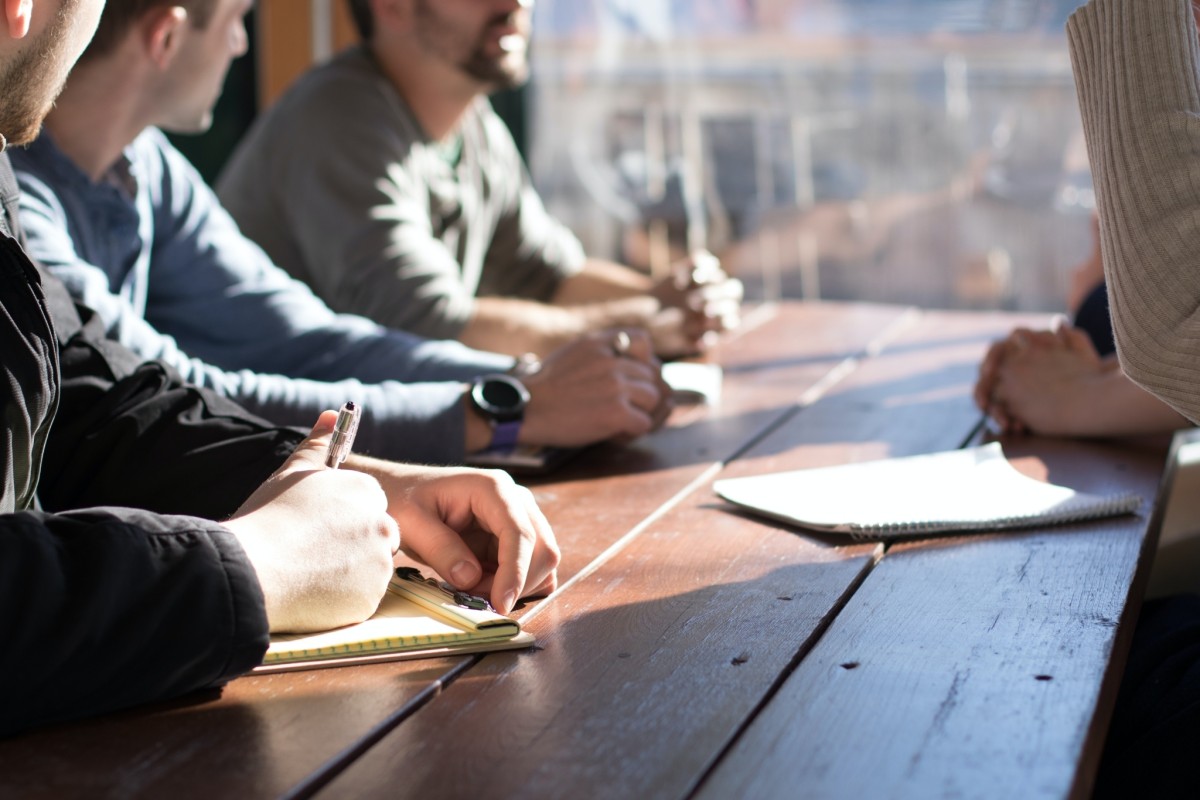People around a table taking notes during a meeting