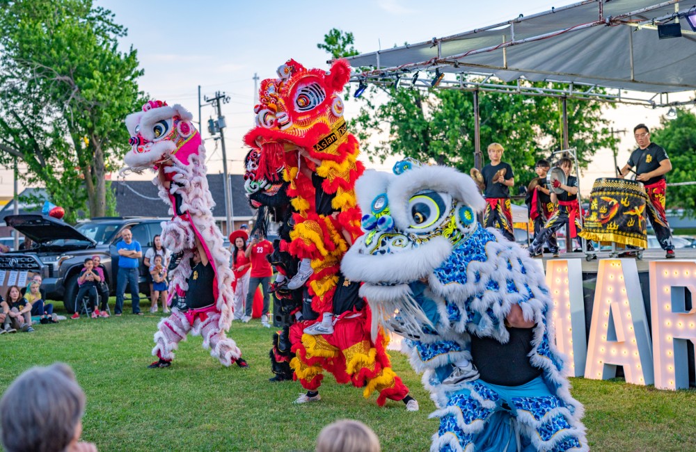 Lion dancers perform in front of a stage where musicians play on traditional drums.