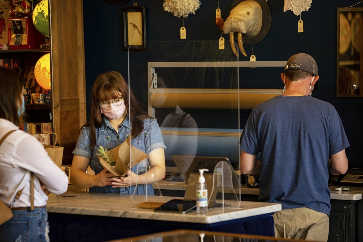 A shop clerk wraps a small succulent plant for a customer.