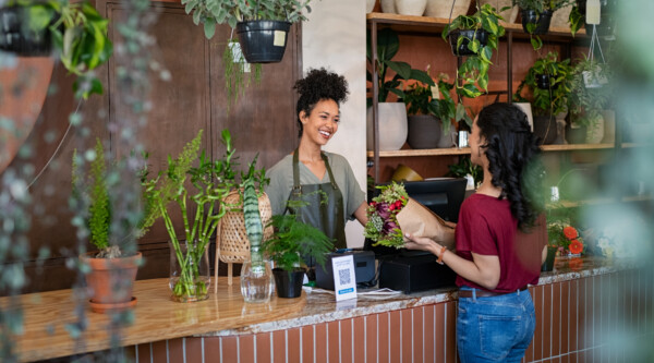 A woman at a counter buys flowers from another woman
