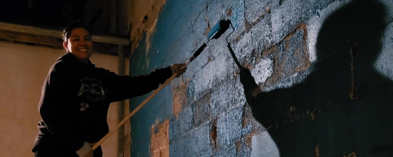 Woman painting brick facade.