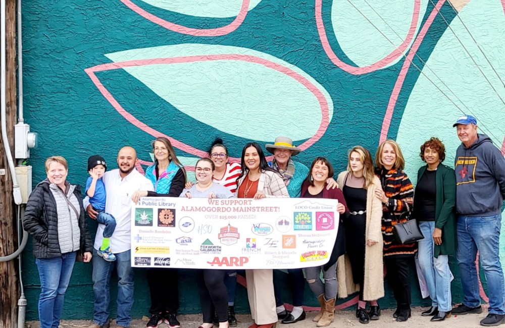 Group of people posing in front of sponsor sign.