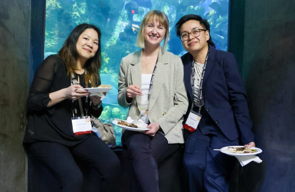 Three people stand in front of an aquarium tank.