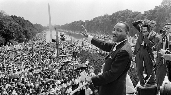 Black and white photo of Martin Luther King Jr. delivering a speech to a large crowd in DC
