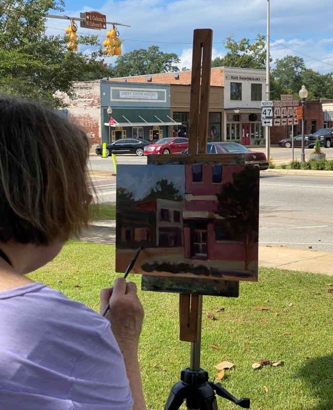A woman paints downtown buildings.
