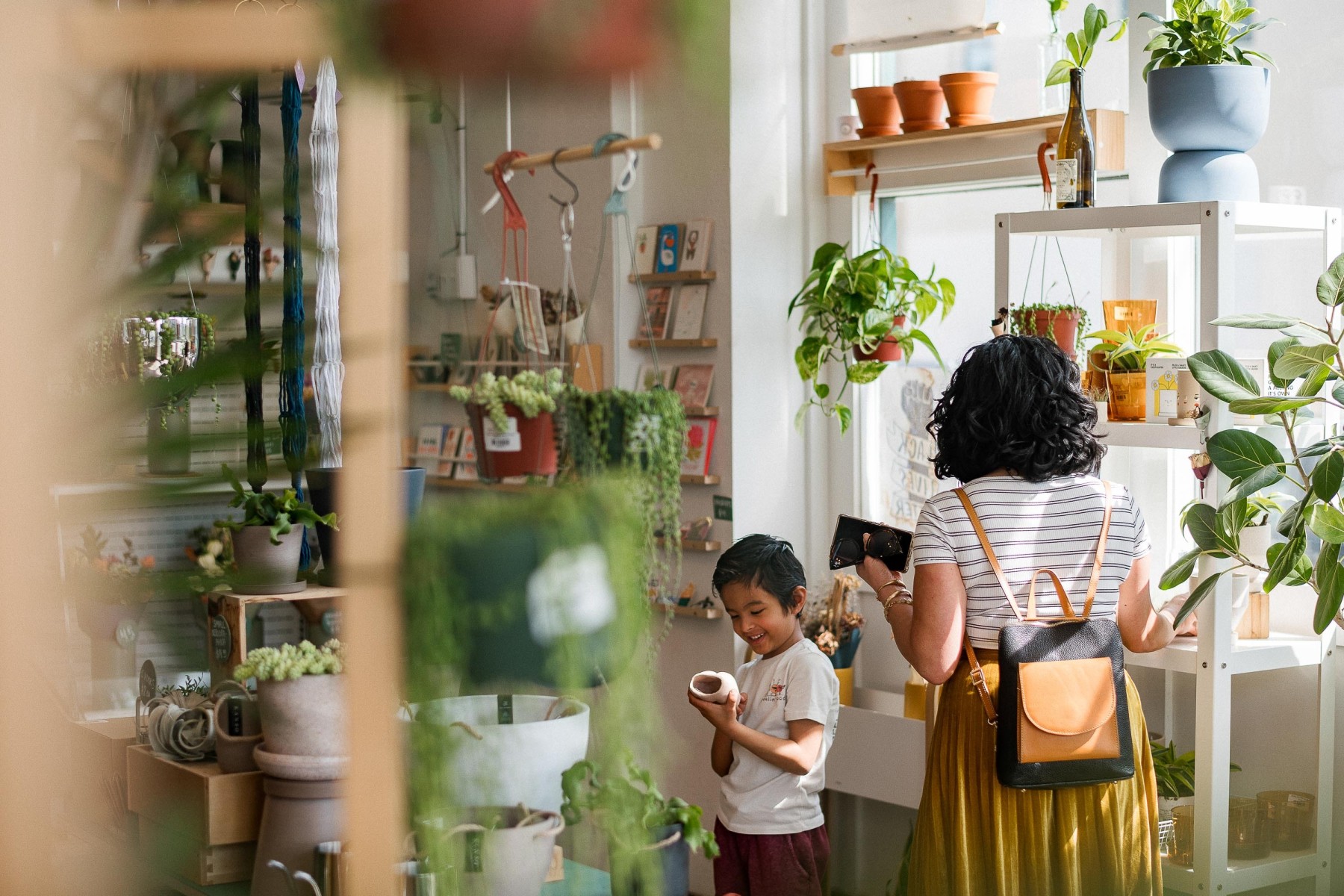 A woman and a boy looking at potted plants in a small shop