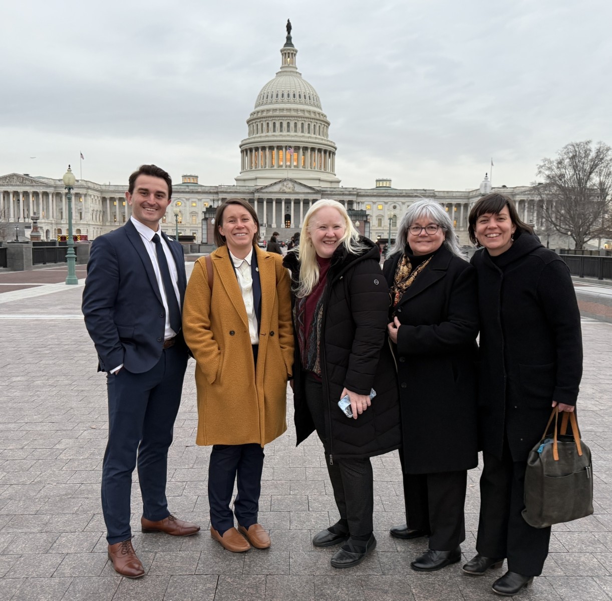 A group of people posing in front of the Capitol
