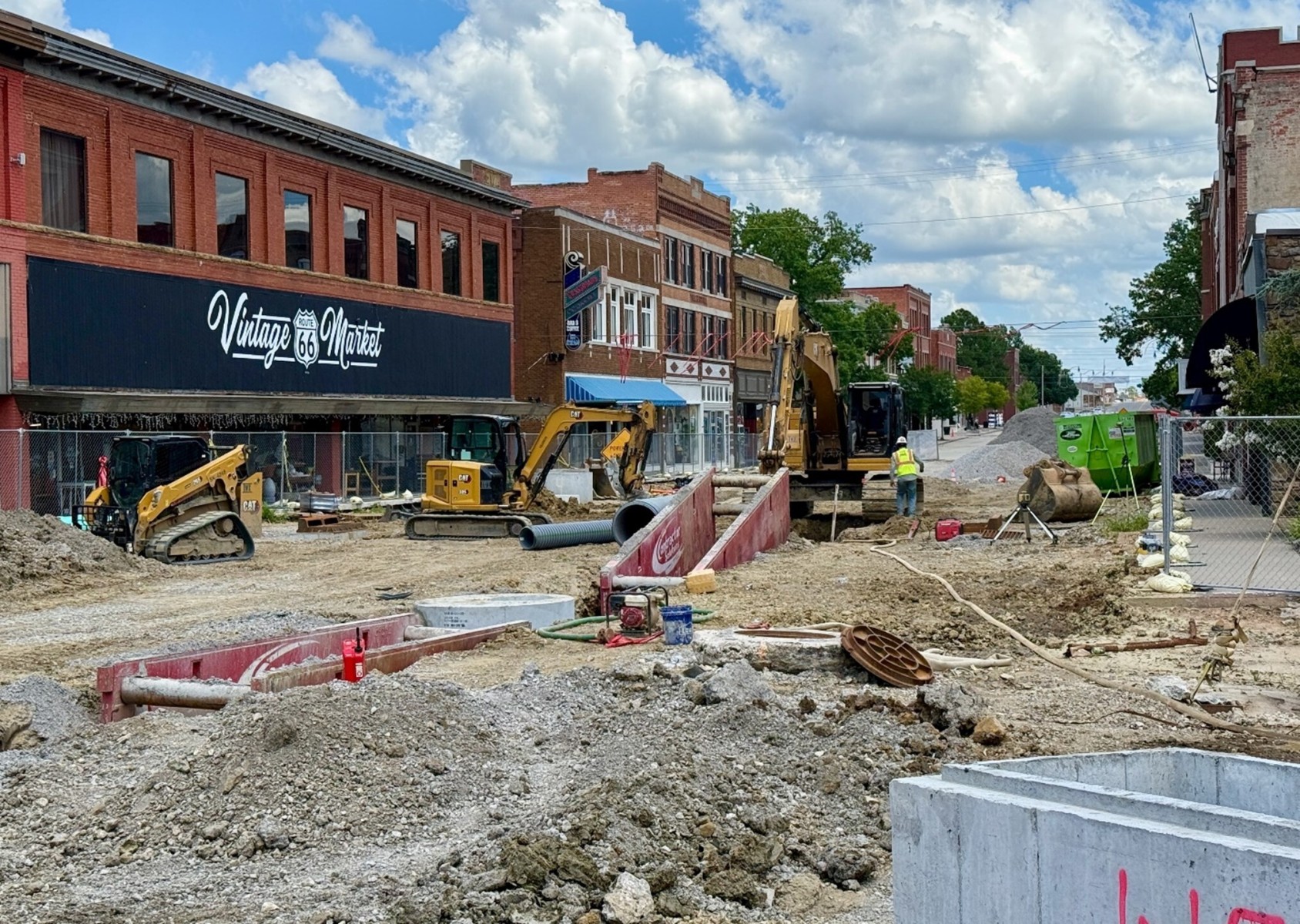 A streetscape construction site with excavators and dirt holes in the street