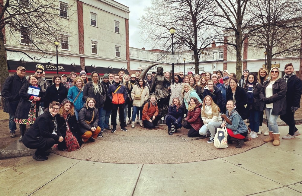 A large group of people pose for a photo in a plaza.