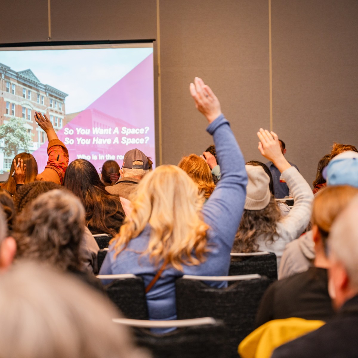 People attending a presentation raise their hands.