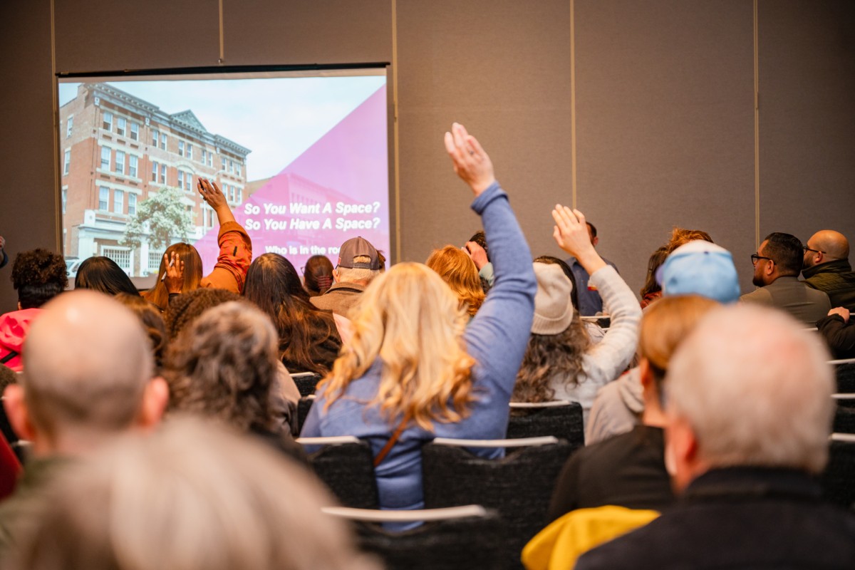 People attending a presentation raise their hands.