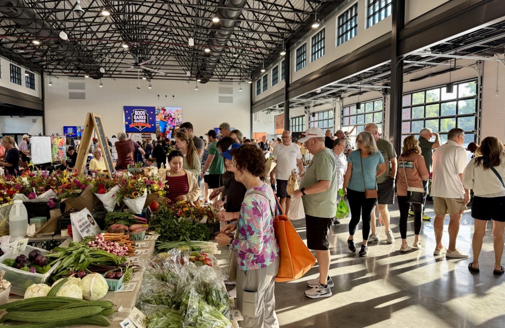 People browsing stalls in a sunny indoor farmers market complex