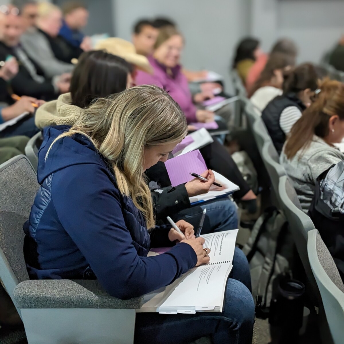 People sit in a theater, taking notes.