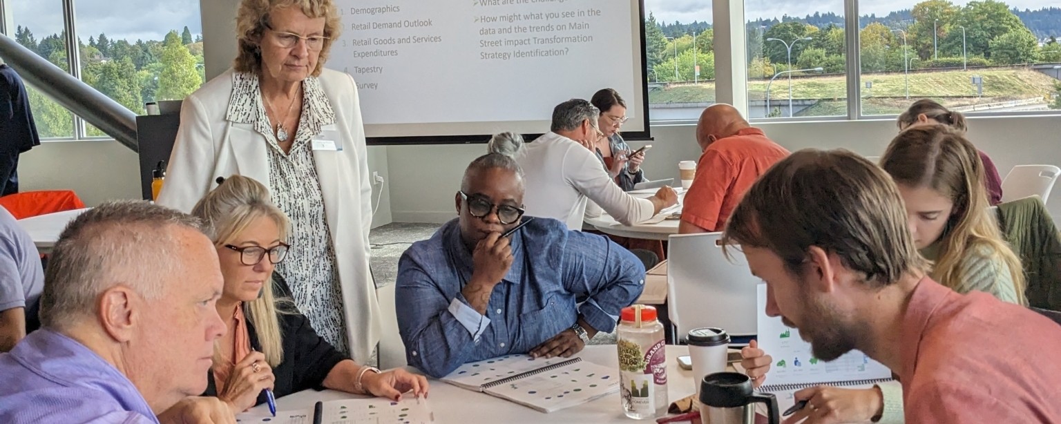 People engaged in active discourse while gathered around a table and reviewing materials.