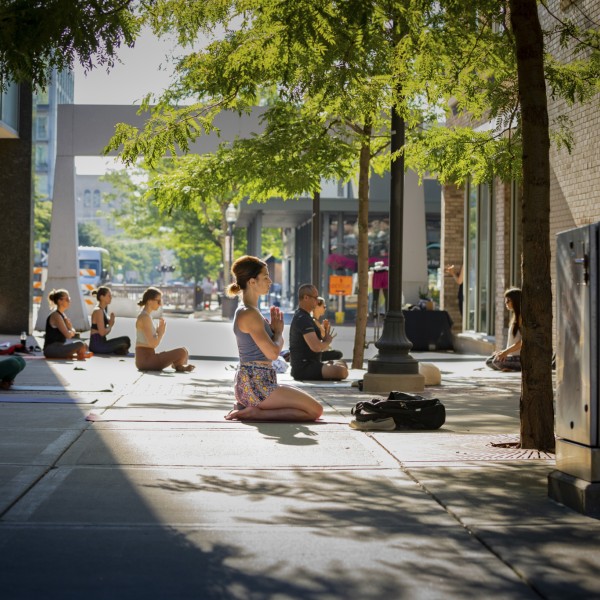 People practicing yoga in an outdoor plaza.