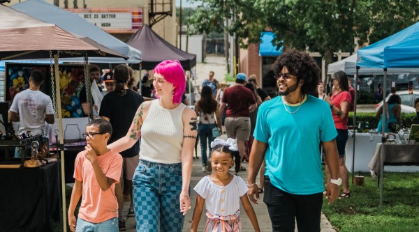 A family walking through a busy street market with vendor stalls