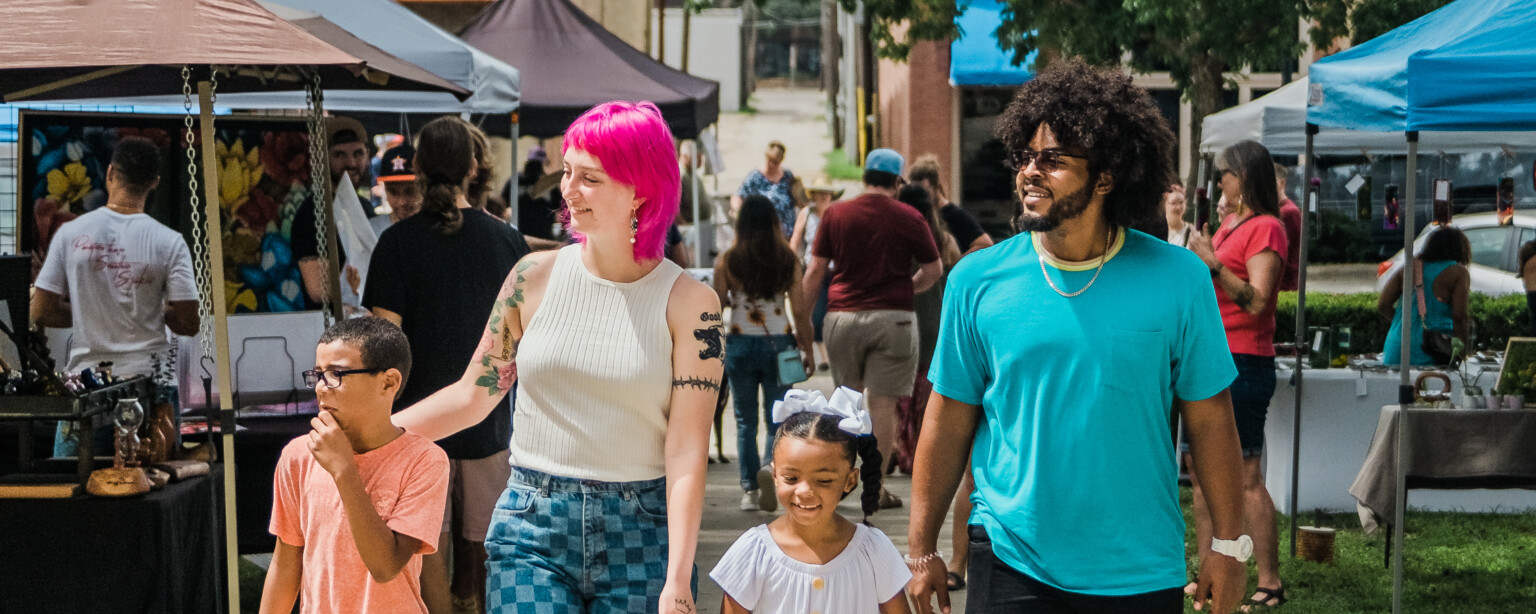A family walking through a busy street market with vendor stalls