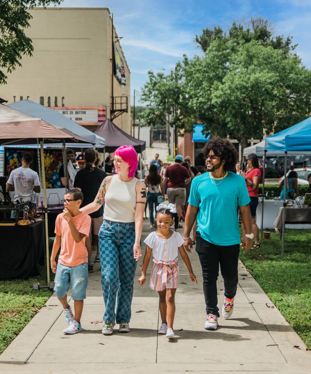 A family walking through a busy street market with vendor stalls