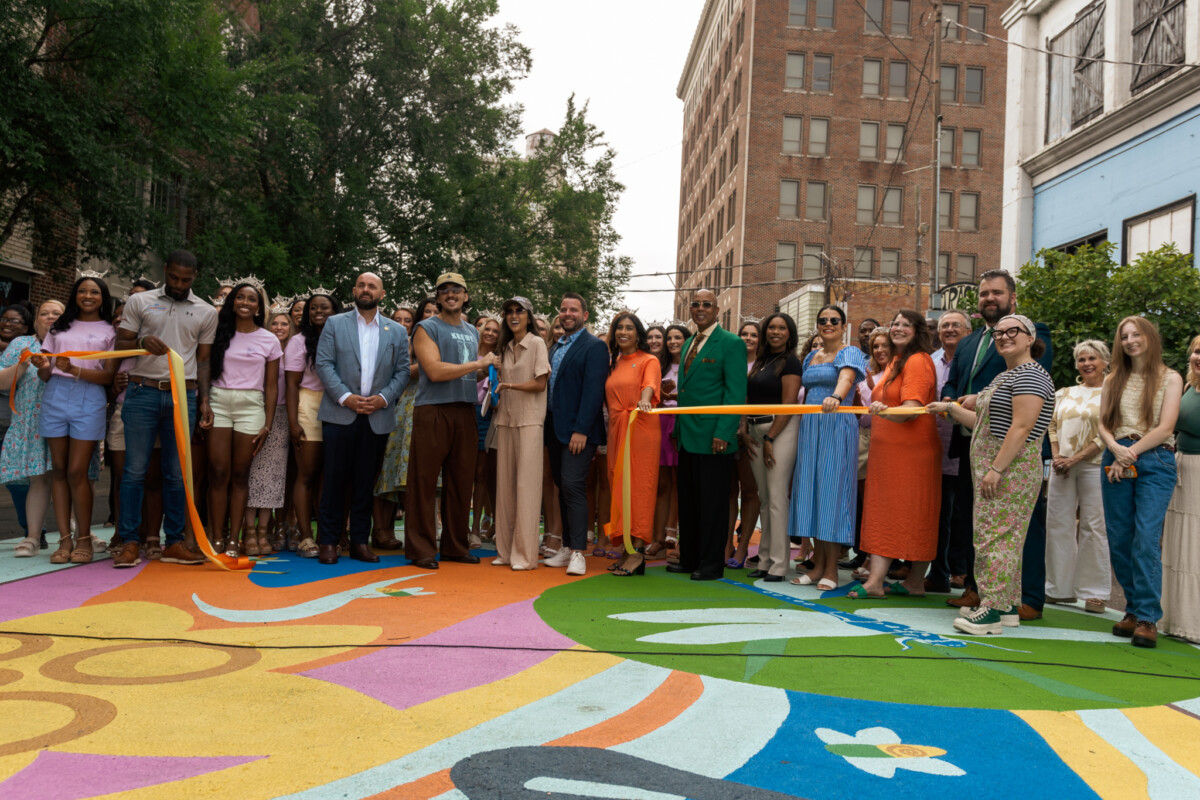 Group of people at a ribbon cutting ceremony on a colorfully painted street