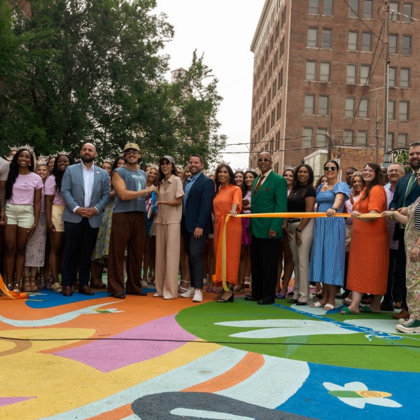 Group of people at a ribbon cutting ceremony on a colorfully painted street