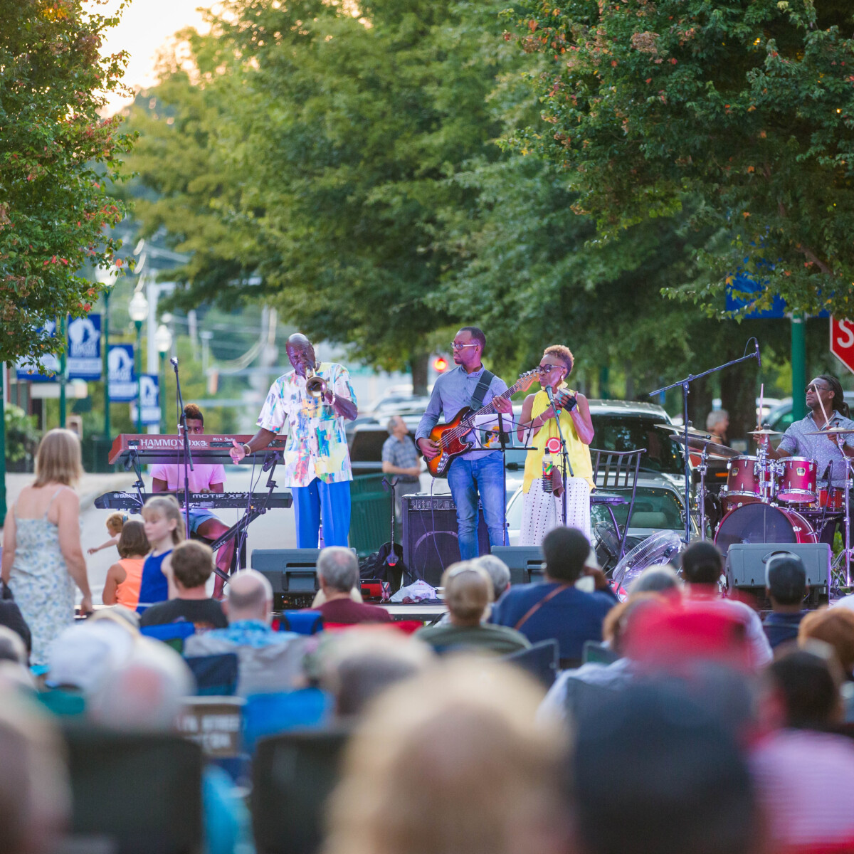 A band performs for a large crowd at an outdoor concert.