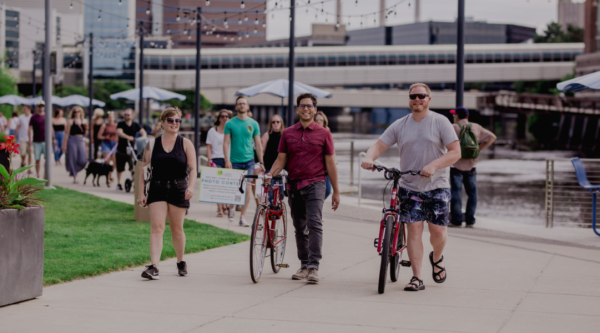 People walking their bikes across a downtown plaza