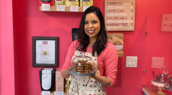 Elisa Lyew, owner of Elisa's Love Bites in New York, NY, smiles and holds a tray of cookies in her bakery.
