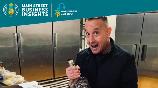 Man in industrial kitchen holds bottle of whiskey